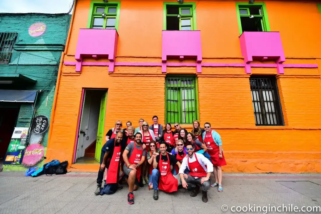 Grupo con delantales frente a la fachada naranja de la casa en Barrio Bellavista