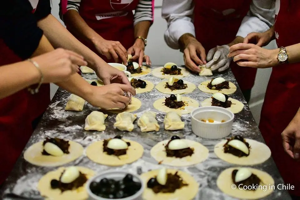 Manos rellenando empanadas de pino